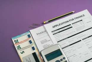 Finance application form; invoice; euro banknotes; calculator; and pencil arranged on purple surface for tech-business con...